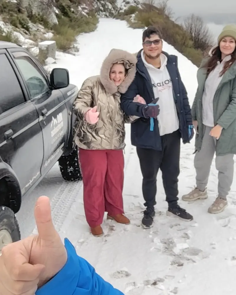 Clientes da 100 Montanhas junto ao jipe da empresa num trilho com neve na Serra da Estrela
