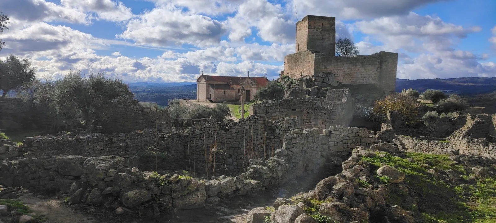 Aldeia histórica com igreja, castelo e ruínas de pedra