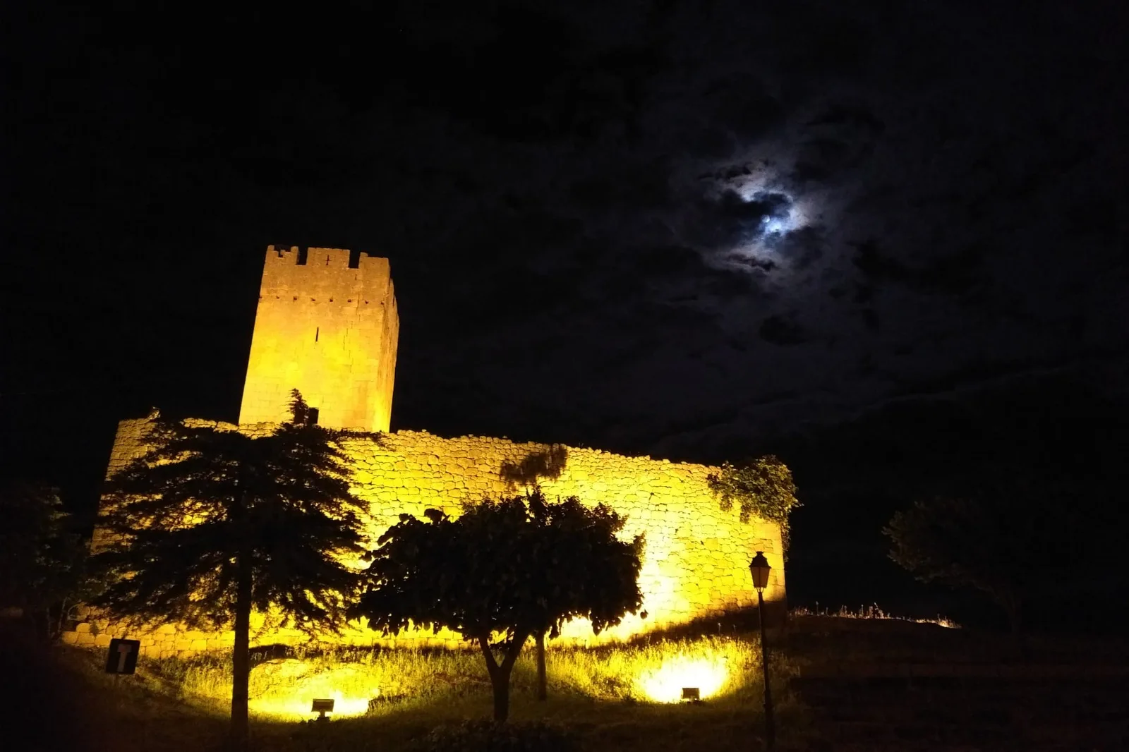 Muralha e torre iluminadas sob a lua