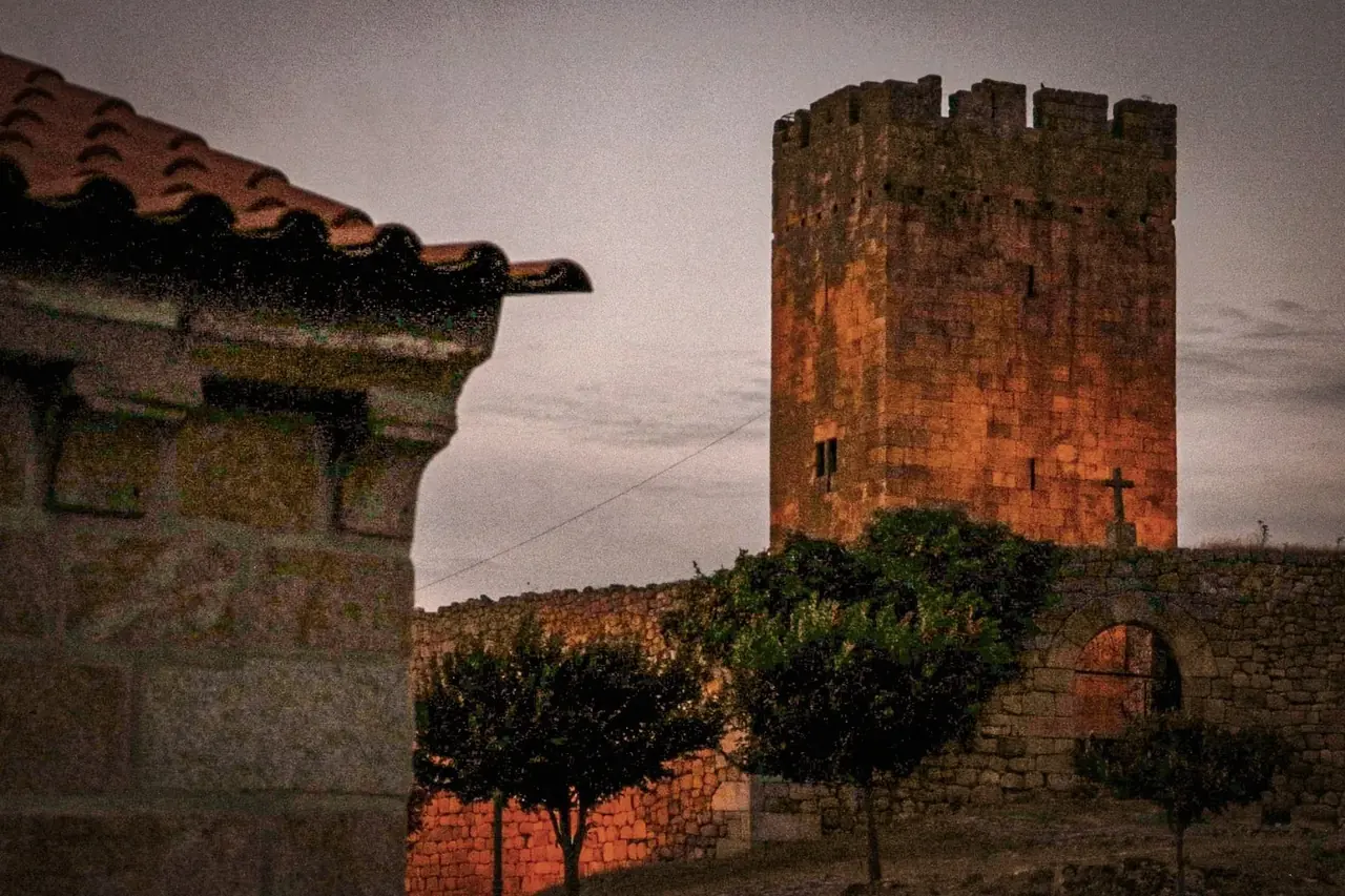 Torre de piedra iluminada junto a una aldea histórica