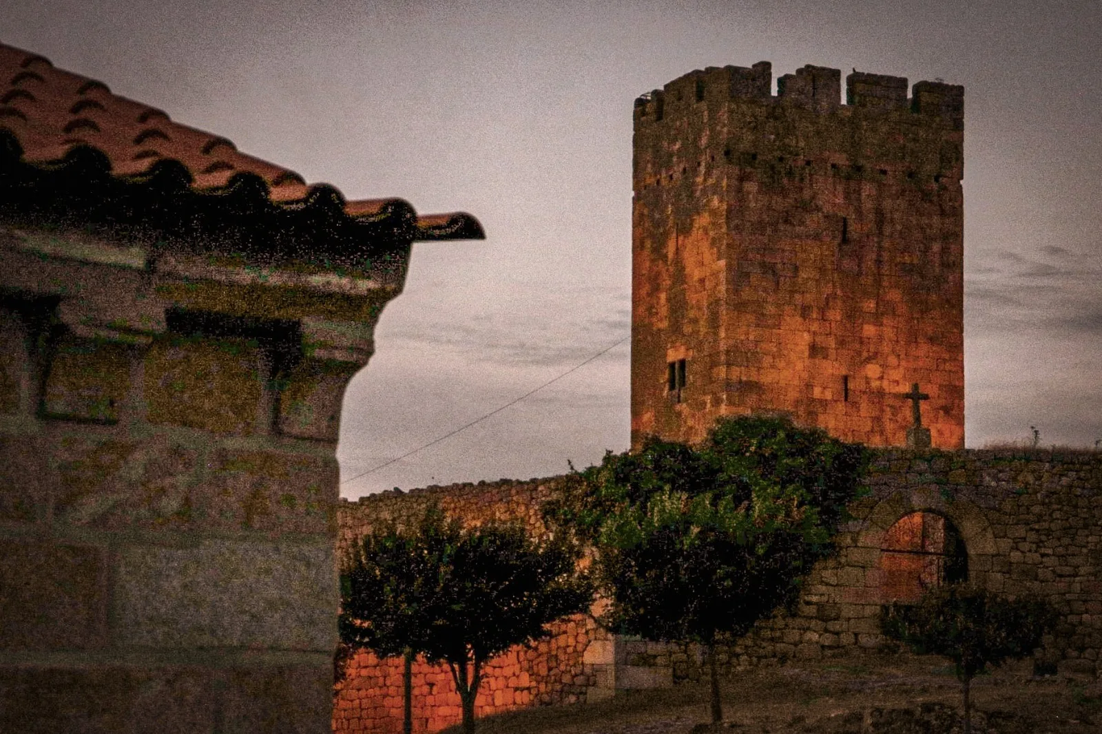 Torre de pedra iluminada junto a uma aldeia histórica
