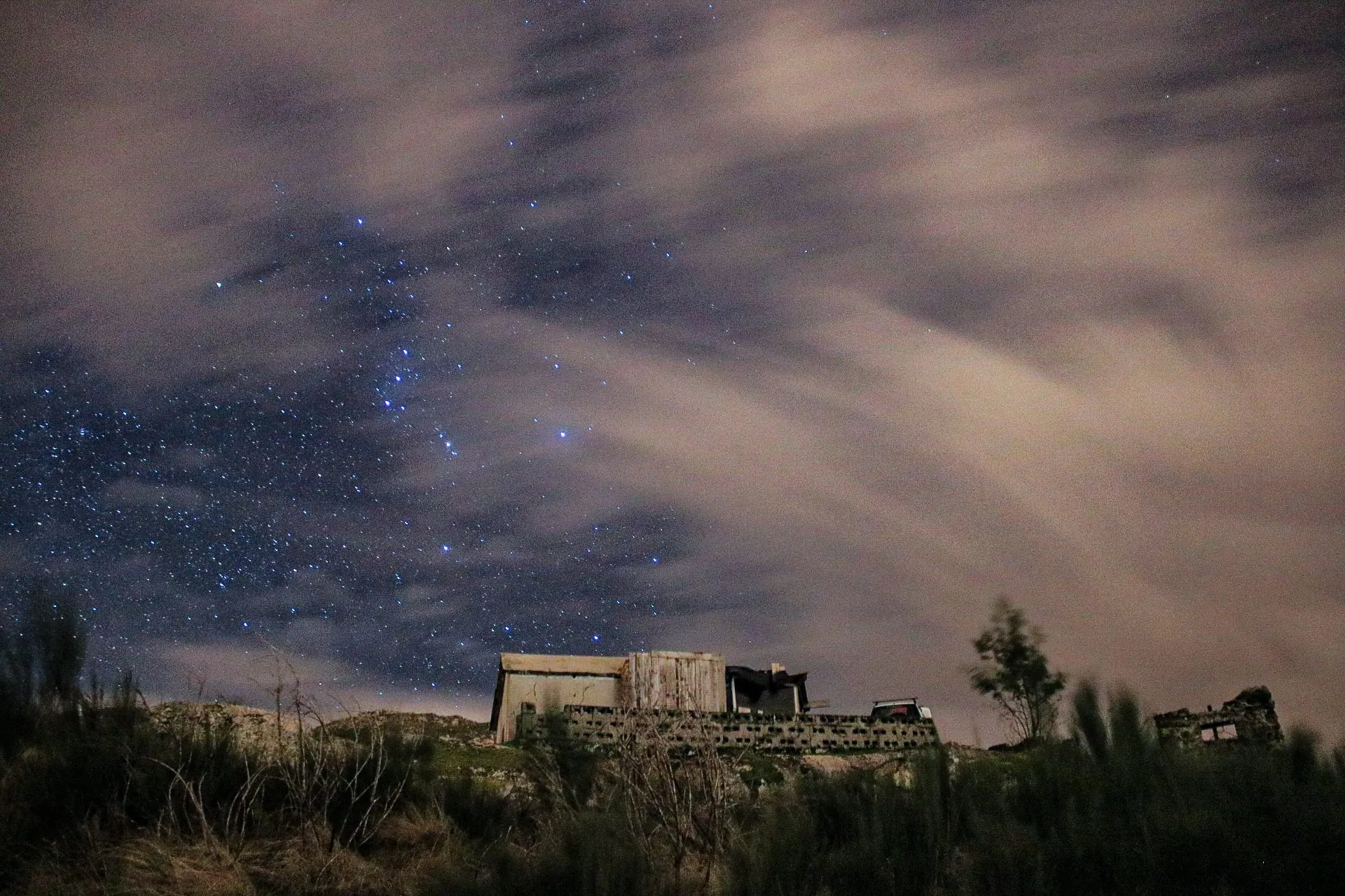 Estrelas entre nuvens com ruína em primeiro plano