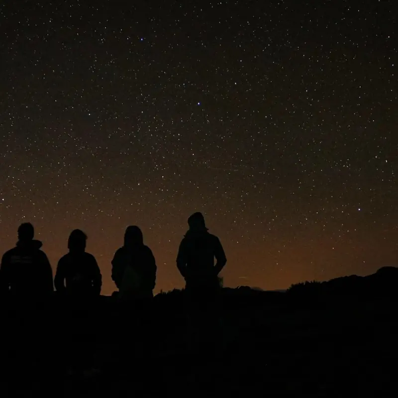 Grupo contemplando el cielo estrellado desde un mirador de la Sierra de la Estrella en la experiencia de observación de estrellas de 100 Montanhas