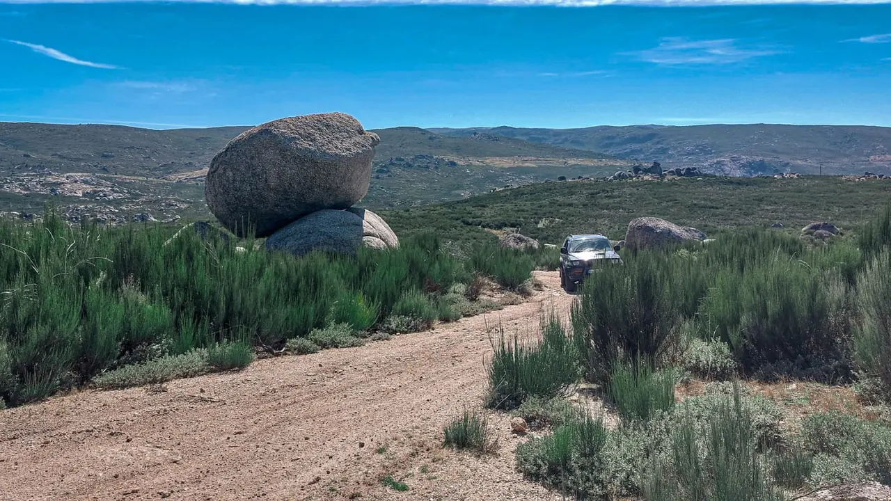 Jipe da 100 Montanhas num estradão da Serra da Estrela no verão, entre mato verde e penedos de granito